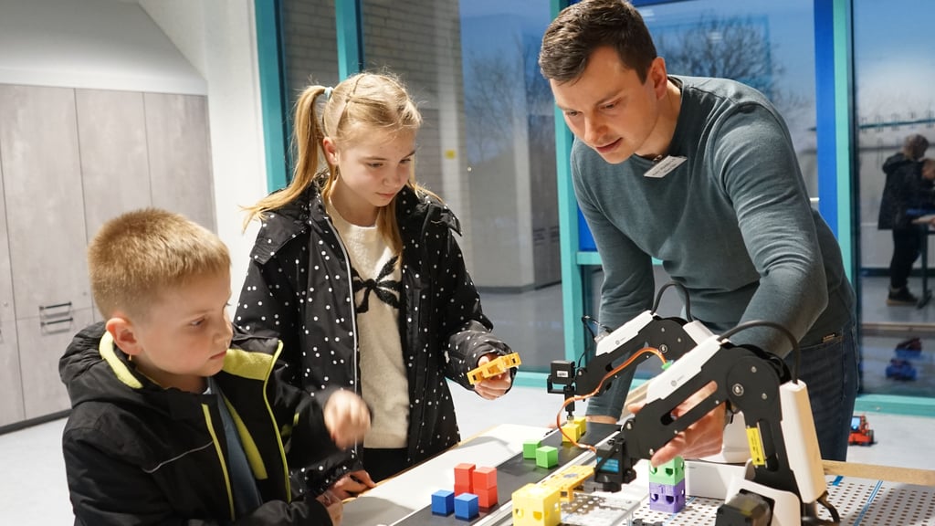 Techniklehrer Robert Hedderich zeigt Sophia und Anton, wie Roboter im Unterricht programmiert werden.
