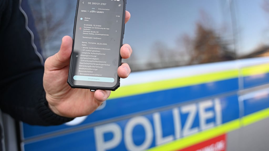 Ein Polizeibeamter aus Sachsen-Anhalt hält ein Smartphone mit der App „resQnect“ an der Polizeiinspektion in Dessau-Roßlau in der Hand.