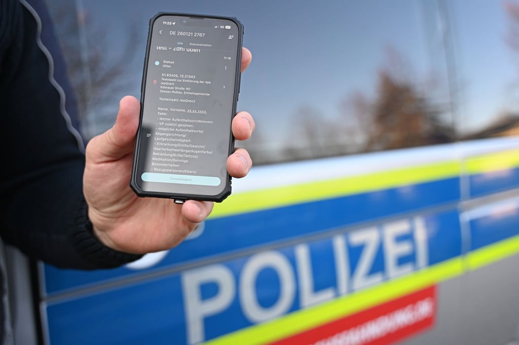 Ein Polizeibeamter aus Sachsen-Anhalt hält ein Smartphone mit der App „resQnect“ an der Polizeiinspektion in Dessau-Roßlau in der Hand.