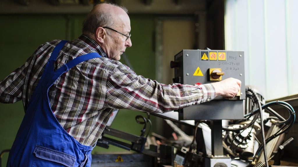Ein älterer Mann arbeitet in einer Werkhalle.
