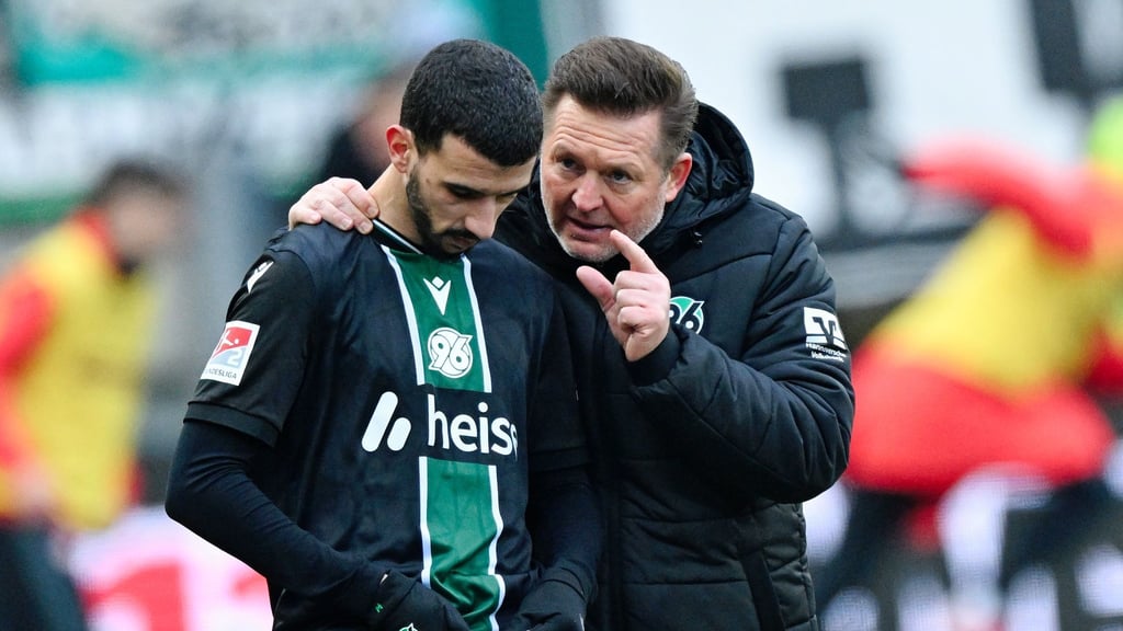 Trainer Christian Titz (r, Hannover 96) spricht bei der Einwechslung mit Waniss Taïbi (Hannover 96).