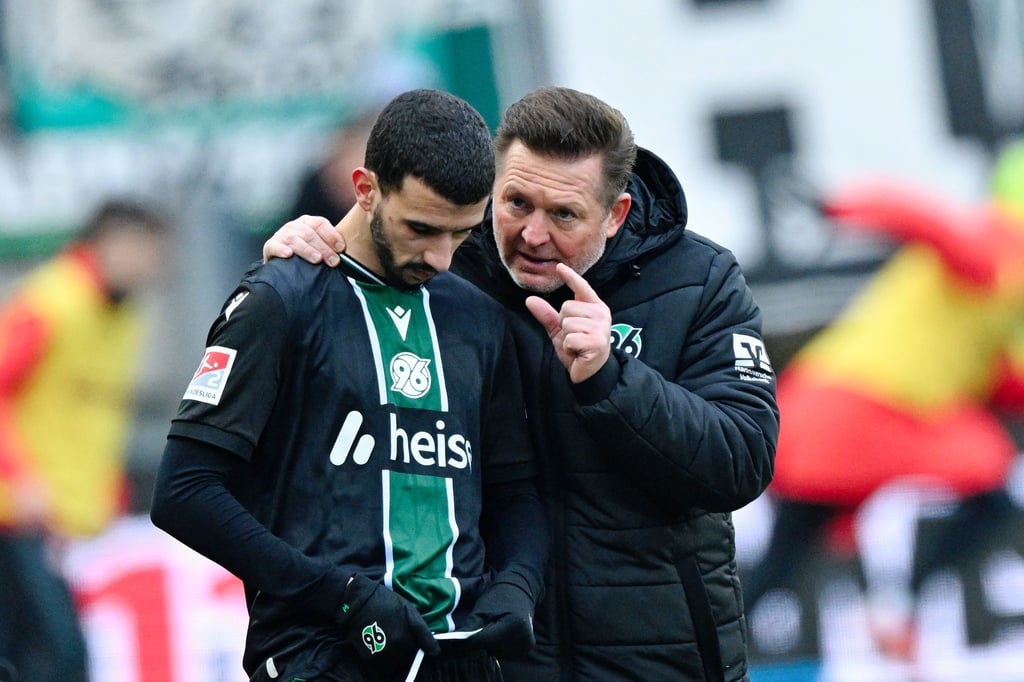 Trainer Christian Titz (r, Hannover 96) spricht bei der Einwechslung mit Waniss Taïbi (Hannover 96).