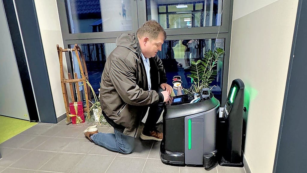 Bürgermeister Hannes Loth (AfD) programmiert den neuen Reinigungsroboter, der in der Kita „Sonnenzauber“ vorerst noch testweise aushilft. 