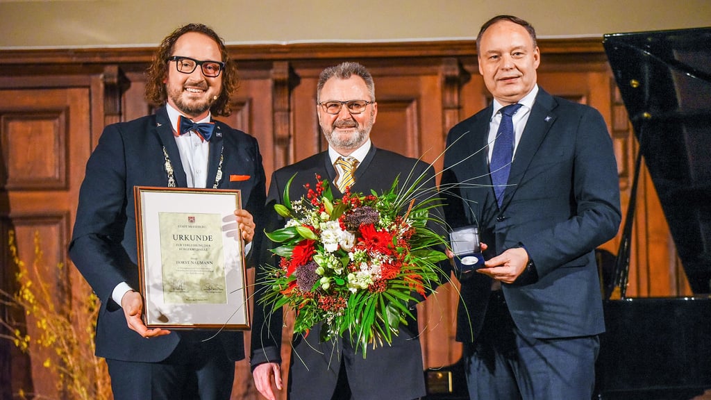 Merseburgs OB Müller-Bahr (l.) und der Ratsvorsitzende Hayn (r.) überreichten Horst Naumann am Donnerstag, 22. Januar 2026, beim Neujahrsempfang die Medaille, eine Urkunde und Blumen. 