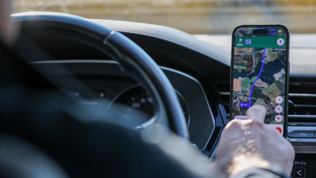 So ist es derzeit erlaubt: Das Handy steckt in der Halterung und wird nur kurz vom Fahrer beachtet. (Symbolbild)