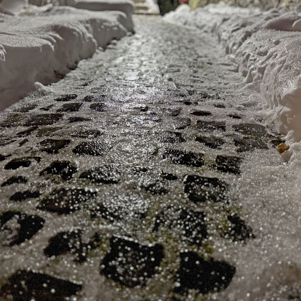 Gefrorener Regen auf Pflastersteinen reflektiert das Licht der Straßenlaterne: Autofahrer in Sachsen-Anhalt müssen sich diese Woche auf glatte Straßen einstellen.