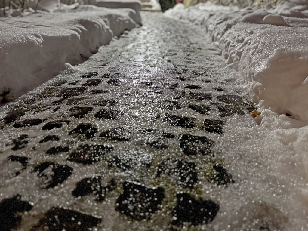 Gefrorener Regen auf Pflastersteinen reflektiert das Licht der Straßenlaterne: Autofahrer in Sachsen-Anhalt müssen sich diese Woche auf glatte Straßen einstellen.