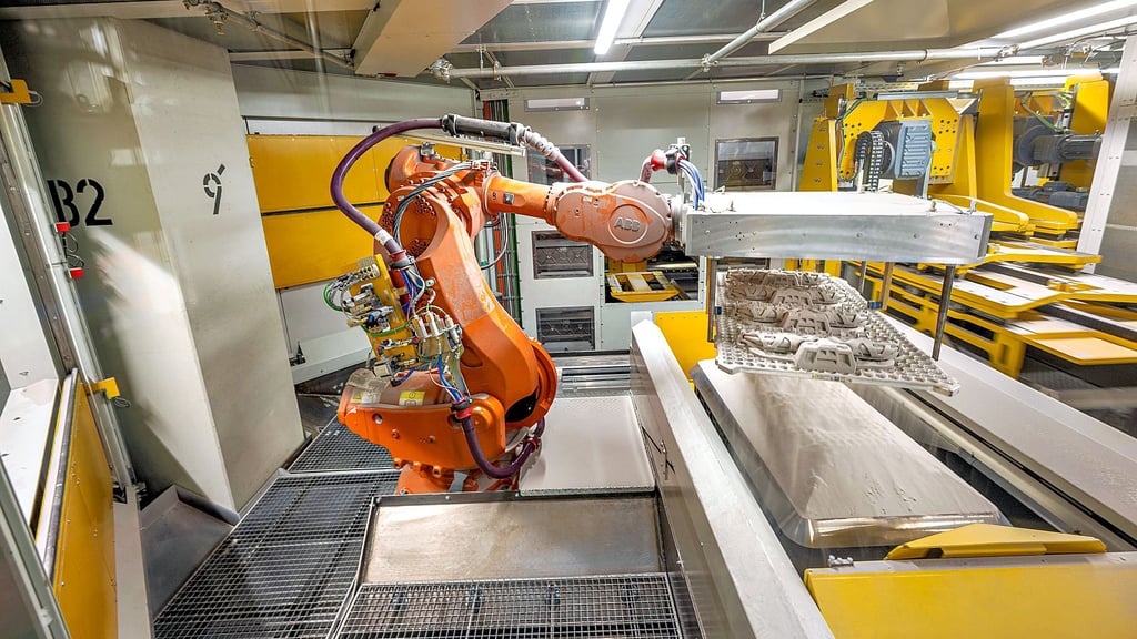 Ein Roboter entnimmt frisch gedruckte sogenannte Wassermantel-Kombikerne für Sechszylinder-Motoren von BMW. Die Technologie stammt von „Laempe Mössner Sinto“ aus Meitzendorf. 