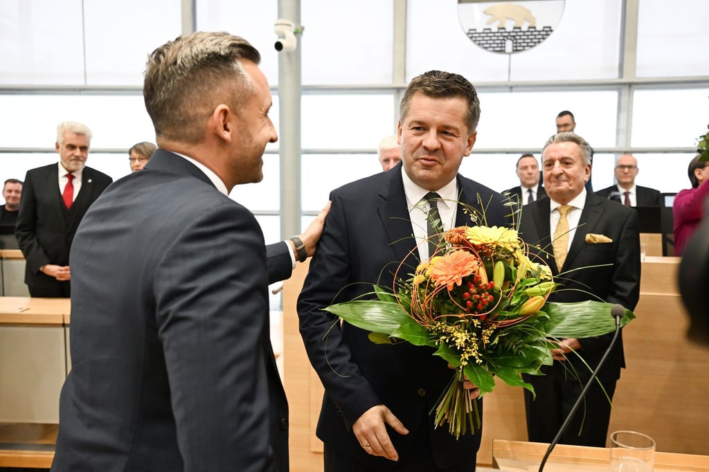 Sven Schulze bekommt Glückwünsche und einen Blumenstrauß vom AfD-Spitzenkandidaten Ulrich Siegmund.