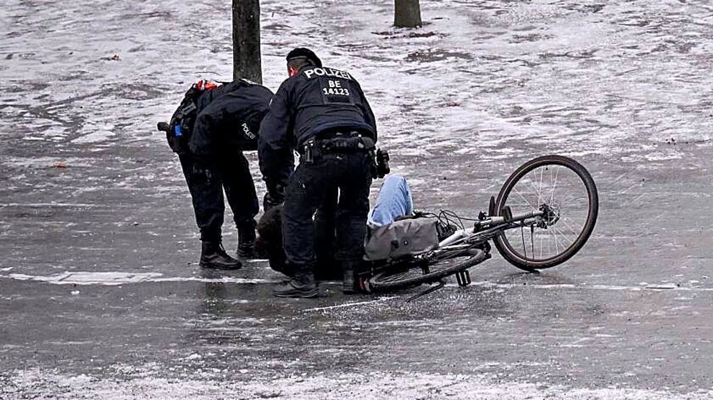 Polizisten helfen in Berlin einem auf Eis gestürzten Radfahrer.