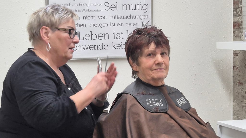 „Sei mutig“ steht auf der Tafel hinter Cornelia Herwegen, die gerade Christel Neumann frisiert. Die Aufforderung hat sie sich zu Herzen genommen.