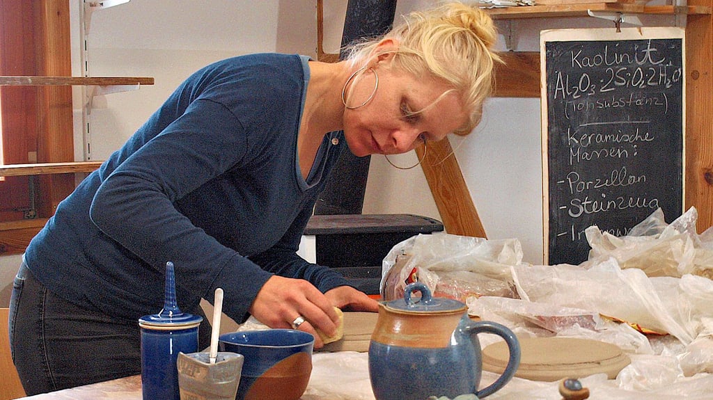 Keramikerin Anna Zorra Bölke gibt den abgedrehten Tellern  in ihrem Schramper Werkstattatelier vorm zweiten Brand den letzten Schliff.