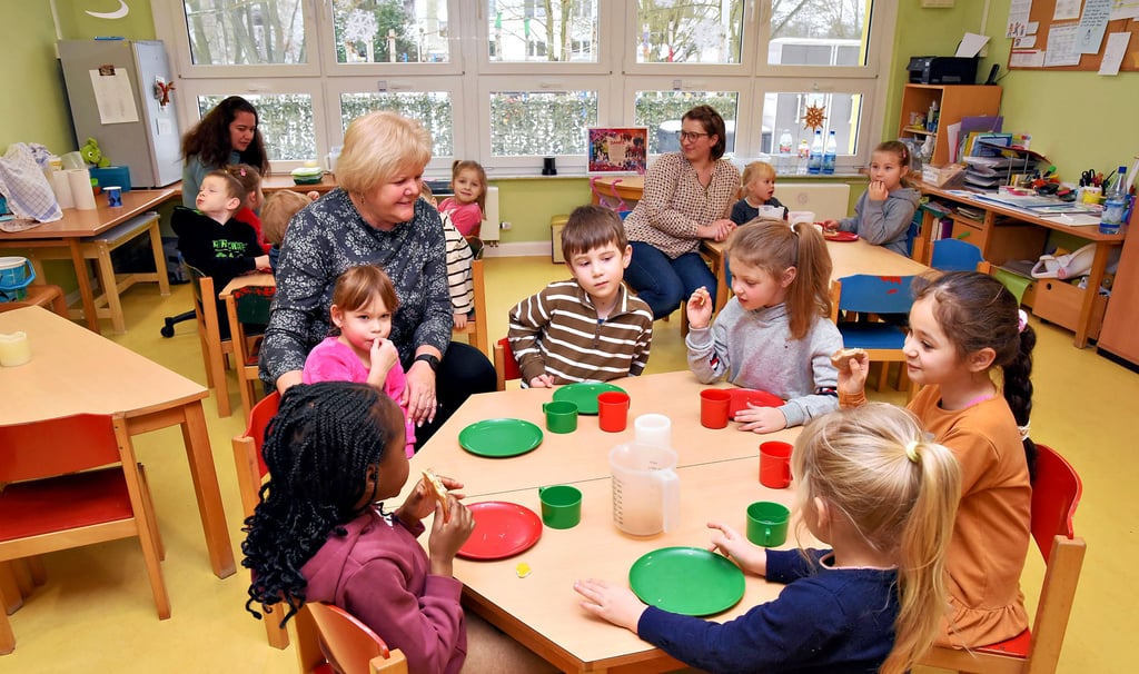 Kinder sitzen mit Erzieherinnen beim Essen in der Integrativen Kita „Spatzennest“ in der Mühlenbreite in Köthen.