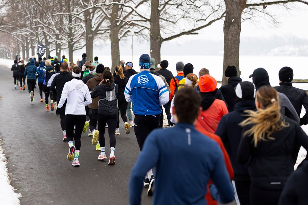 Sportfans laufen bei Winterwetter um den Maschsee in Hannover.
