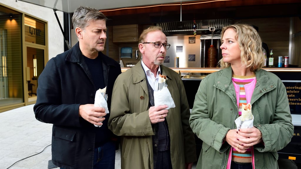 Harald Neuhauser (l, Marcus Mittermeier), Ludwig Schaller (Alexander Held) und Angelika Flierl (Bernadette Heerwagen) stehen vor einem Imbissstand.