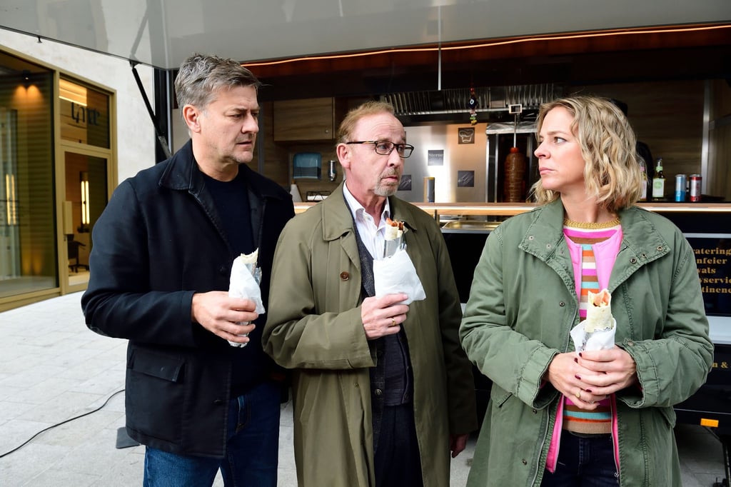 Harald Neuhauser (l, Marcus Mittermeier), Ludwig Schaller (Alexander Held) und Angelika Flierl (Bernadette Heerwagen) stehen vor einem Imbissstand.