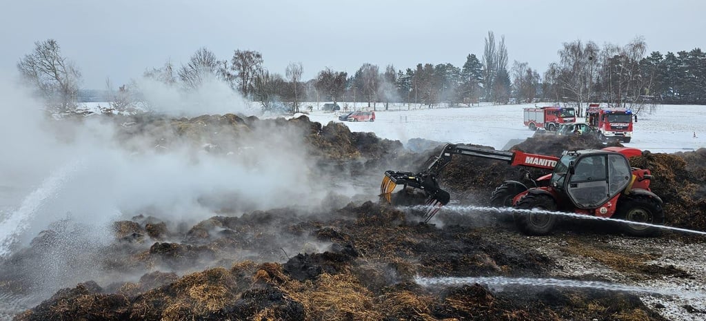 Mit einem Teleskoplader wird der brennende Misthaufen auseinandergezogen, um Glutnester gezielt zu löschen.   