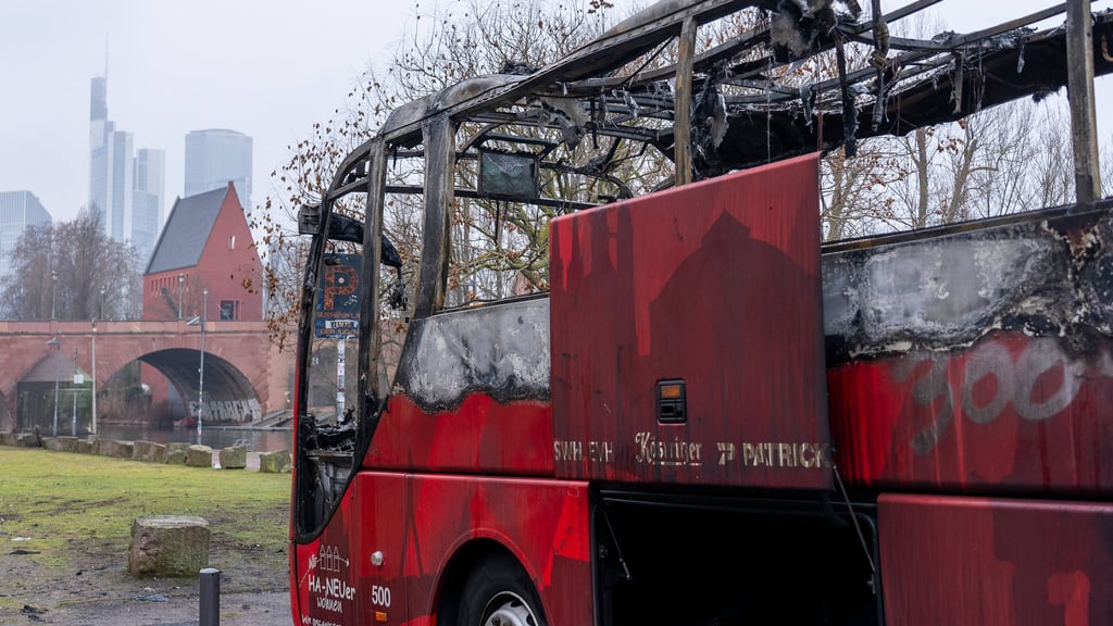 Der ausgebrannte Bus des HFC, im Hintergrund die Skyline von Frankfurt