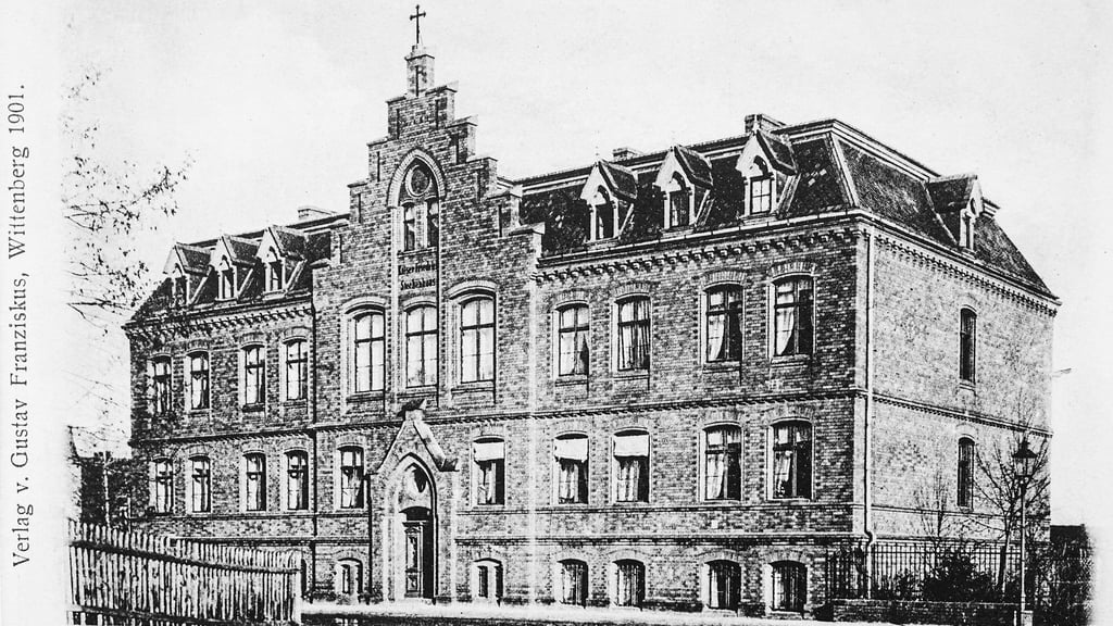 Eine Postkarte, gedruckt 1901, zeigt das 1894 eingeweihte Kaiser-Friedrich-Siechenhaus in der Bachstraße. Hier fanden alte und pflegebedürftige Wittenberger, wie etwa Kaufmann Seelmann, Aufnahme.