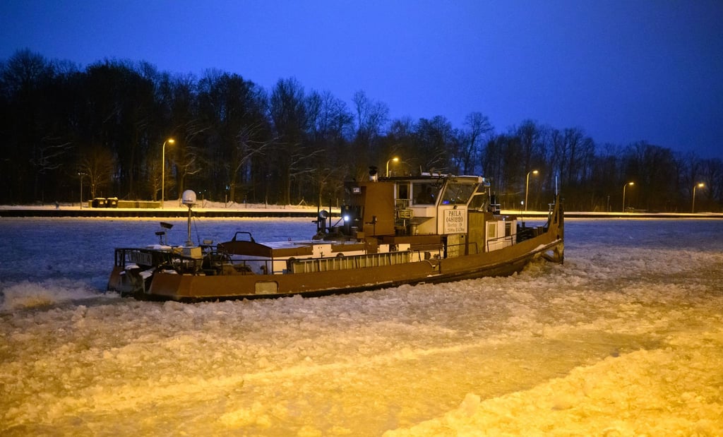 Ein Eisbrecher dreht am frühen Morgen auf dem vereisten Mittellandkanal vor der Schleuse Anderten Runden.
