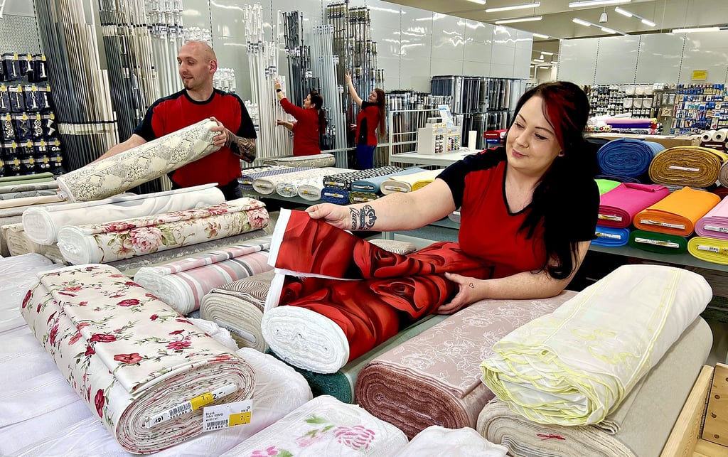 Tedox-Mitarbeiter wie Gardinenbereichsleiterin Janine Bergel (r.) und Haushaltswarenbereichsleiter Torben Vollstedt füllen bereits die Tische des neuen Marktes mit Waren wie Stoffe.  
