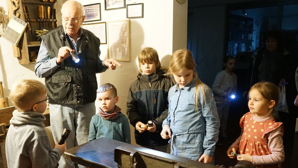 Günter Töpfer erklärt den Kindern bei der Taschenlampenführung die Werkzeuge einer Stellmacherwerkstatt.