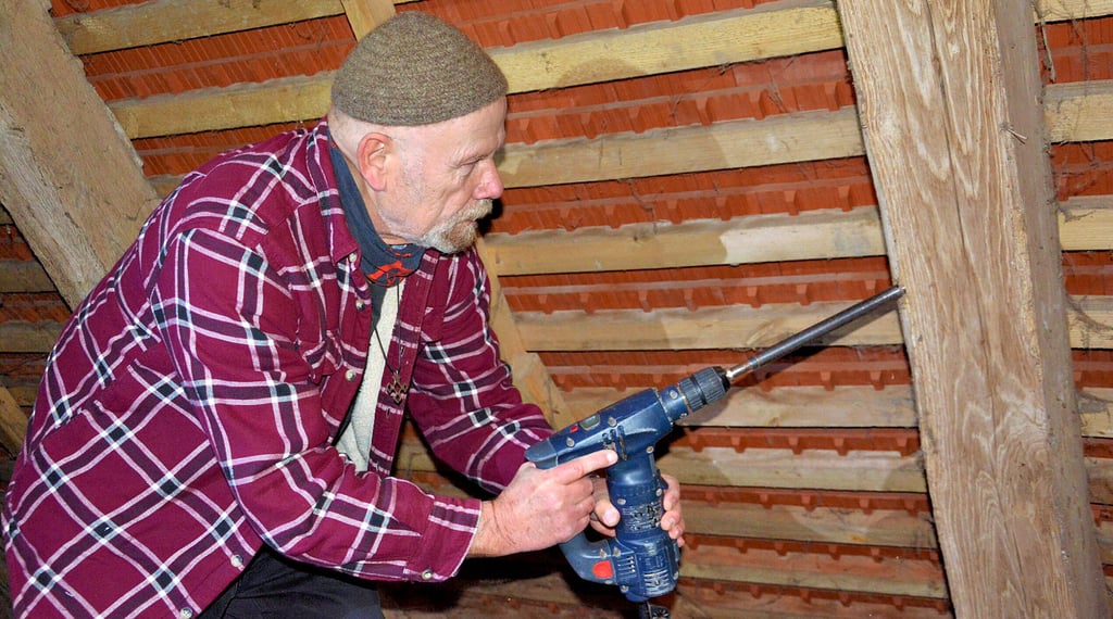 Ulf Frommhagen nimmt mit dem Hohlbohrer vom Gebälk der Kirche in Groß Schwechten eine Probe für die dendrochronologische Datierung.