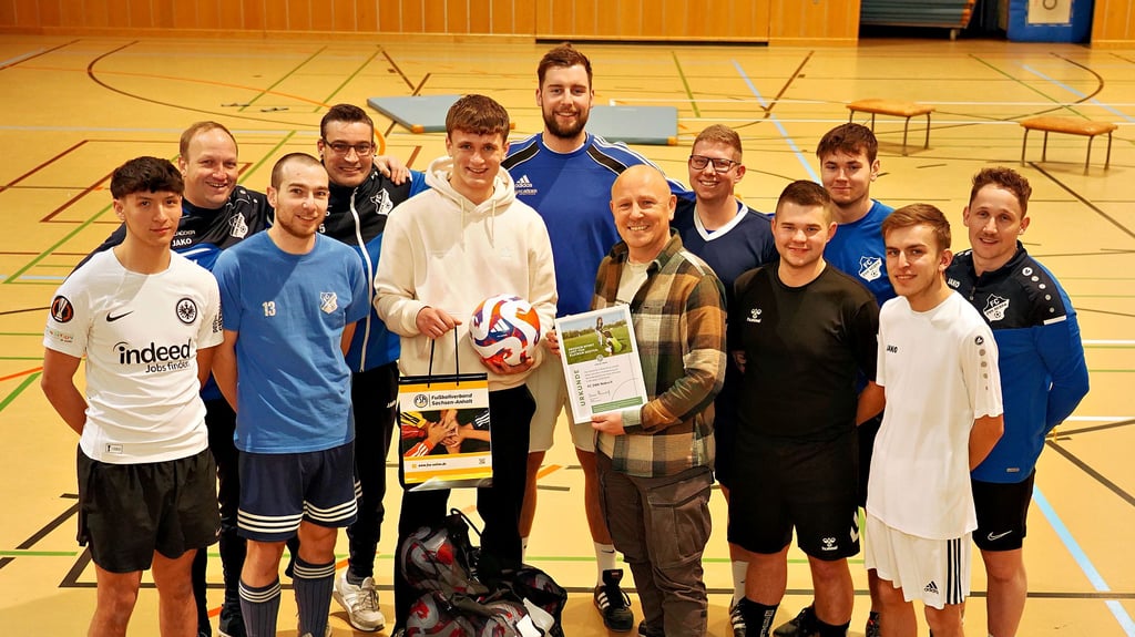 Finn Melzian vom Landesfußballverband FSA (5. v. l.) übergibt Preis und Trainingsbälle an Andreas Henzel (6. v. r.) und dessen Nebraer Team.
