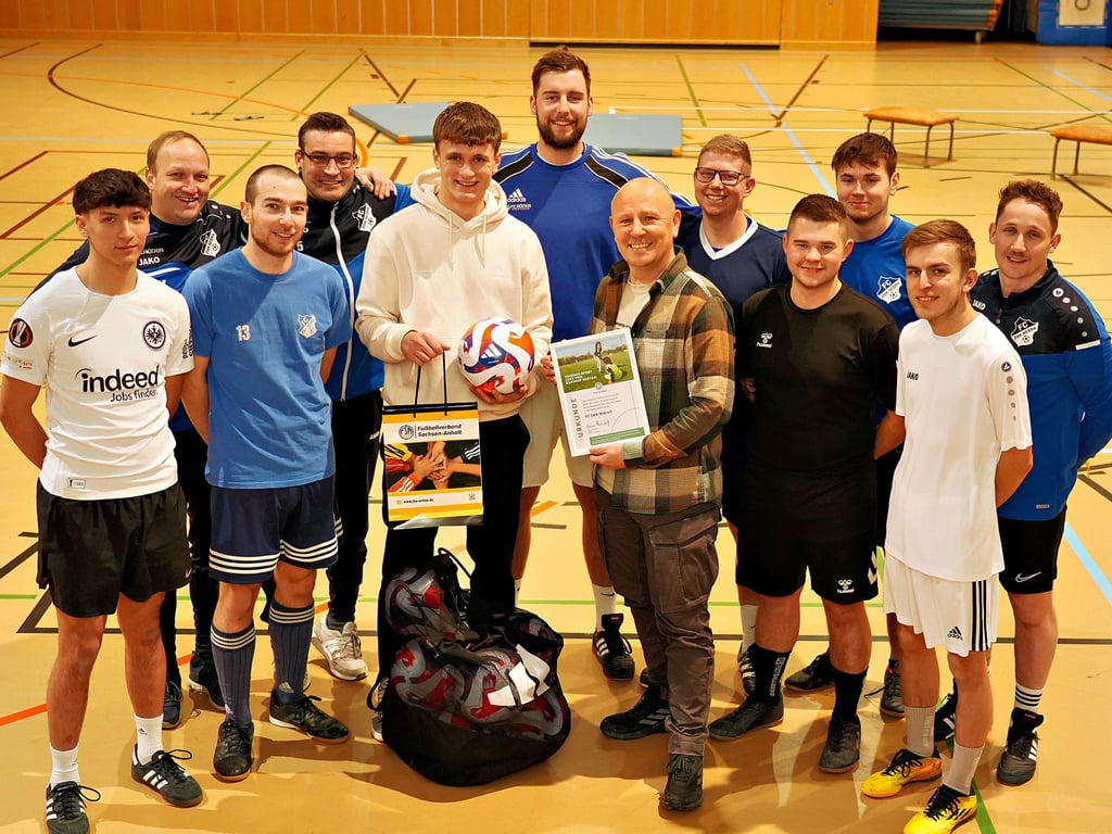 Finn Melzian vom Landesfußballverband FSA (5. v. l.) übergibt Preis und Trainingsbälle an Andreas Henzel (6. v. r.) und dessen Nebraer Team.