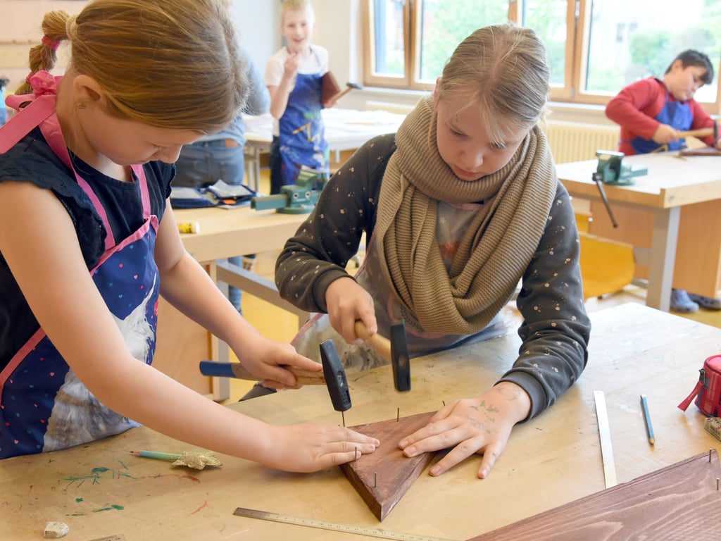 Zwei Mädchen schlagen im Werkunterricht Nägel in ein Holzbrett. Aus Sicht der Handwerkskammer kommt das Werken in den Lehrplänen in Sachsen-Anhalt zu kurz. 