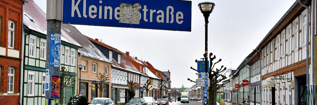 Ein ausgeblichener, aber weiterhin fest sitzender Aufkleber sorgt dafür, dass das Schild Kleine Straße für Vorbeifahrende schwierig zu lesen ist. 