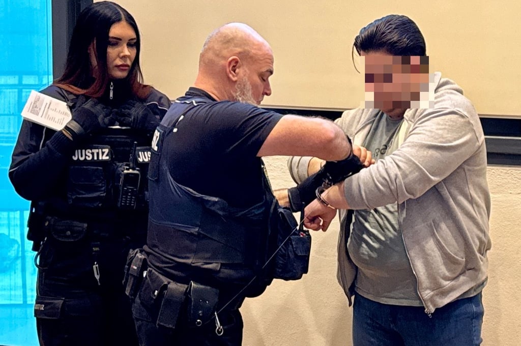 Ein Justizbeamter nimmt dem Angeklagten vor dem Drogenprozess die Handschellen ab.