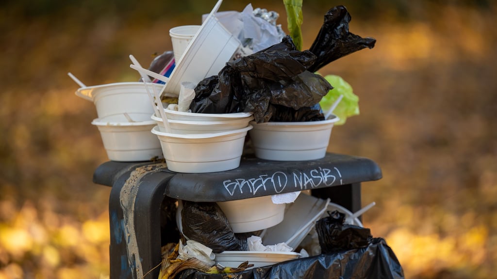 Benutzte Einwegbehälter stapeln sich in einem überfüllten Mülleimer. Eine Verpackungssteuer könnte helfen, Müll einzusparen. In Magdeburg ist die Abgabe noch nicht vom Tisch.