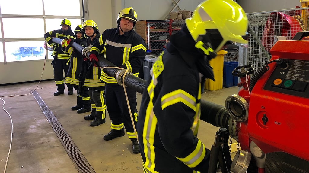 Praktische Übung für die künftigen Einsatzkräfte bei verschiedenen Feuerwehren: Die Saugschläuche sind zusammengekoppelt, die fertige Saugleitung wird an die Pumpe angeschlossen.