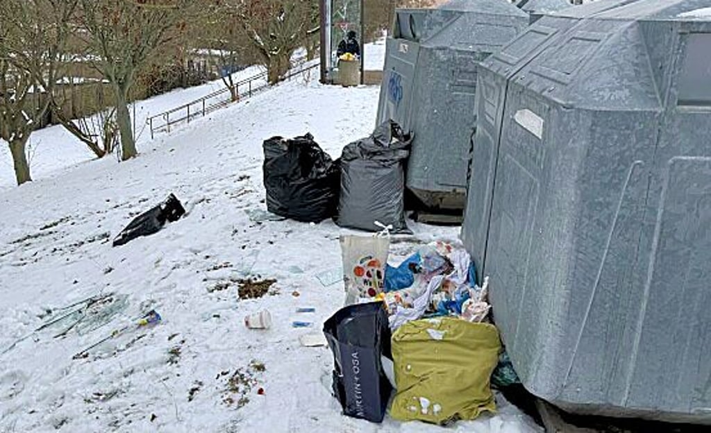Müll, Altkleider  und Glasscherben neben dem Container  