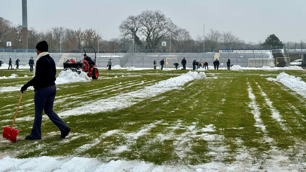 Freiwillige räumen Schnee von der Spielfläche im Dessauer Paul-Greifzu-Stadion
