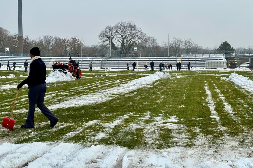 Freiwillige räumen Schnee von der Spielfläche im Dessauer Paul-Greifzu-Stadion