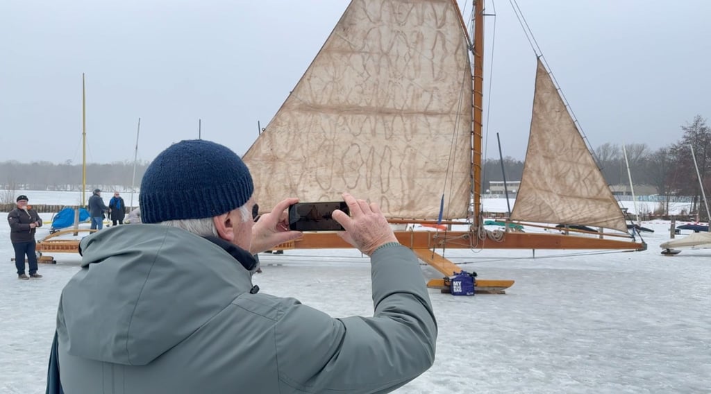 Ein Mann fotografiert auf dem zugefrorenen Müggelsee einen großen Eissegler.
