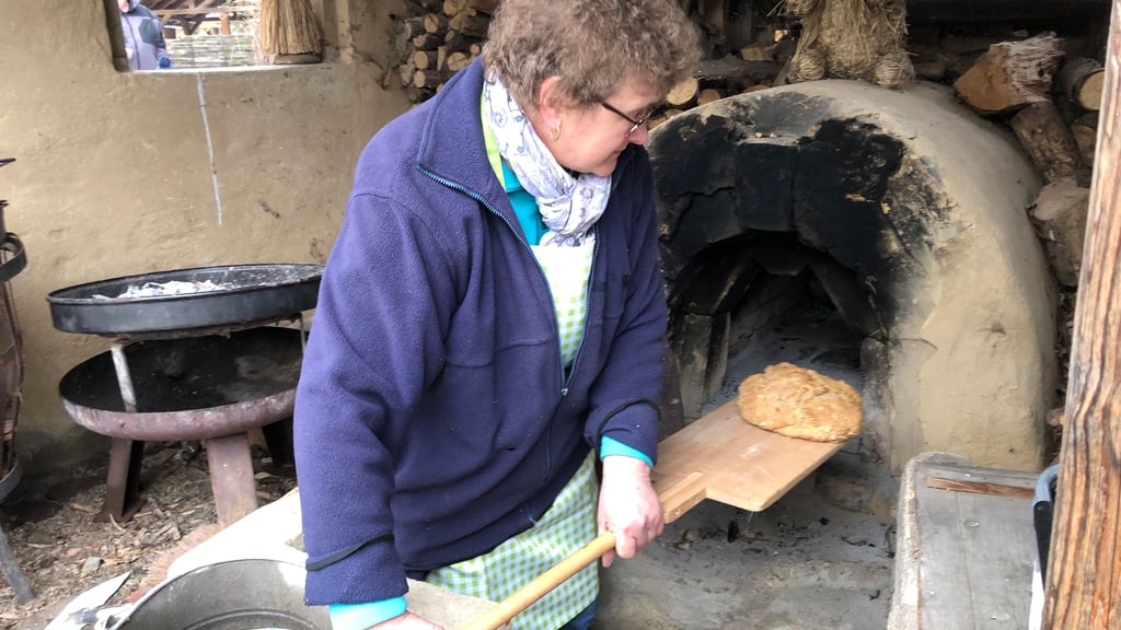 Sylvia Zimmermann, die im Förderverein mitarbeitet, holt ein weiteres Brot aus dem Lehmbackofen im Ökogarten Quedlinburg. 