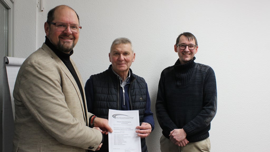 Landrat Martin Stichnoth (l.) übergibt Arnold Schulze aus Klüden ein Teilnahmezertifikat für seine neue Tätigkeit als ehrenamtlicher Betreuer. Christian Roder (r.) vom Betreuungsverein Oschersleben leitet die Schulungen.