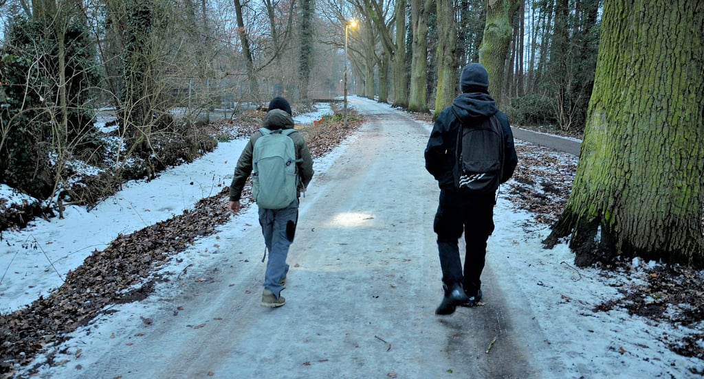 Zwei Schüler tappen im Februar 2026 mit einer Taschenlampe durch den spärlich beleuchteten  Park des Friedens.  