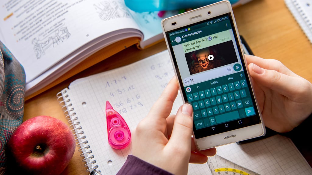 Eine Schülerin liest am Schreibtisch im Gruppenchat eines Messengerdienstes. Sachsen-Anhalt will es seinen Schulen überlassen, ob sie die private Handynutzung verbieten. 