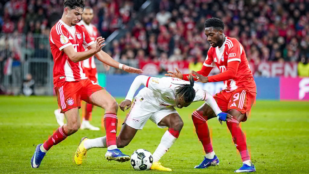 Yan Diomande kann sich nicht gegen Bayerns Alexandar Pavlovic (l.) und Alphonso Davies durchsetzen
