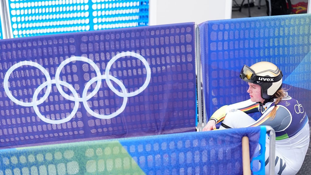 Emma Aicher sitzt nach ihrem Aus im Super-G frustriert im Zielbereich von Cortina d'Ampezzo.