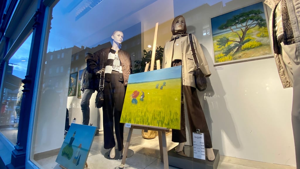 Hinter einem Schaufenster an der Breiten Straße in Wernigerodes Fußgängerzone stellt eine Künstlerin ihre Werke aus.