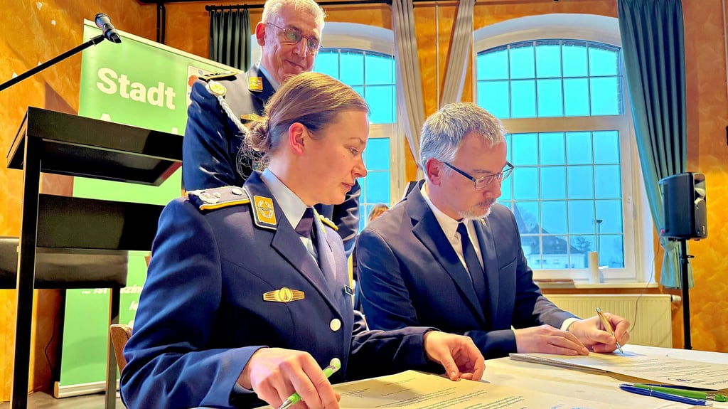 Stabschefin Simone Epple  und  Bürgermeister  Stefan Schmidt unterzeichnen die  Urkunden, Mario Reihs beobachtet sie  dabei.