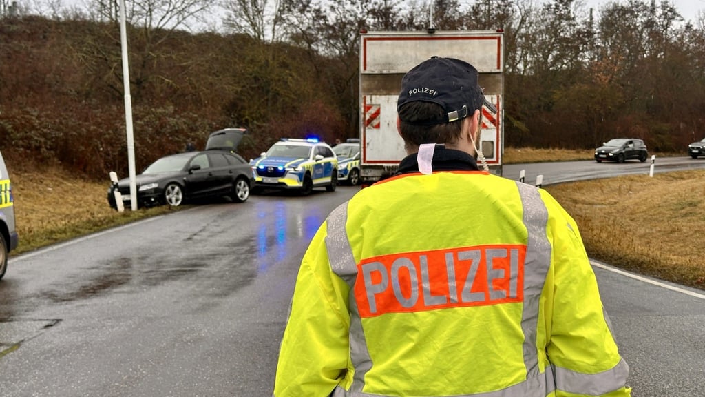 Polizisten regeln an der Unfallstelle den Verkehr, die nur einspurig passierbar ist.