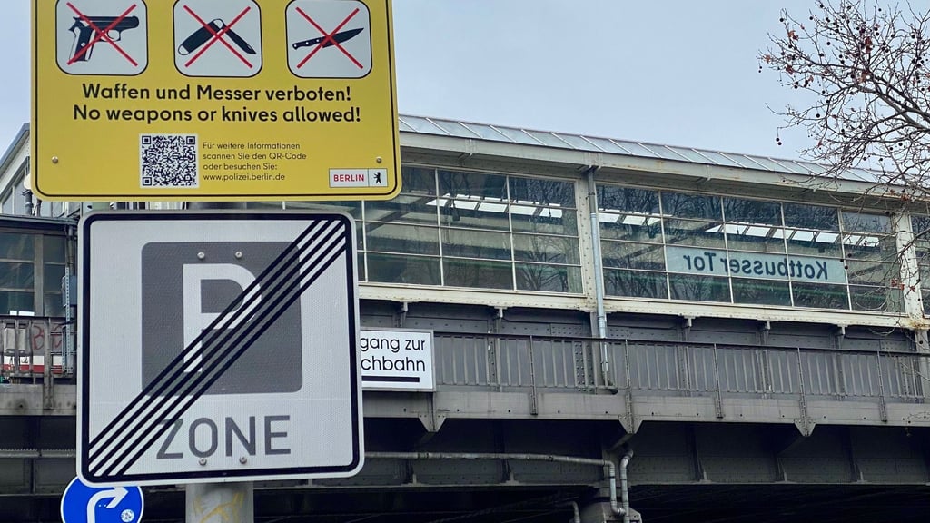 Gelbe Schilder weisen auf die Waffen- und Messerbotszone am Kottbusser Tor in Berlin-Kreuzberg hin.