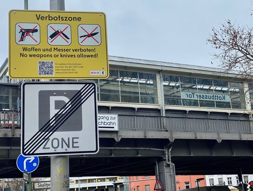 Gelbe Schilder weisen auf die Waffen- und Messerbotszone am Kottbusser Tor in Berlin-Kreuzberg hin.