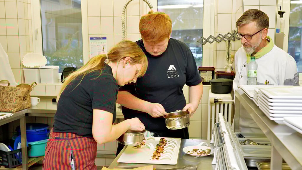 Lehrausbilder Lutz Lehmann (v.r.) blickt Koch-Lehrling Leon Fietkau und Hotelfach-Azubi Selina Rammelt aus Naumburg über die Schulter. 